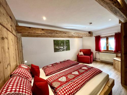 a bedroom with two beds and a red chair at Biobetrieb Lippenhof in Breitnau