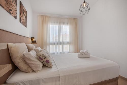 a bedroom with a bed with white sheets and a window at vv Sueño Del Mar in Costa de Antigua
