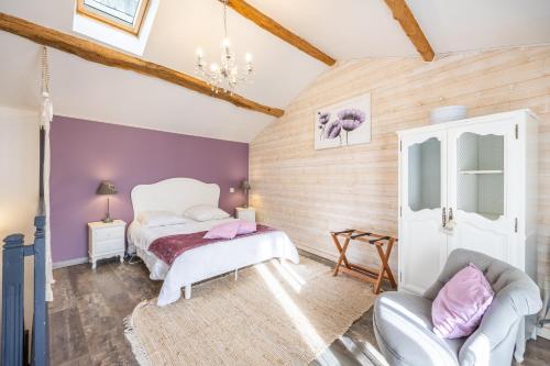 a bedroom with two beds and a chair at Le Clemenceau in Les Épesses