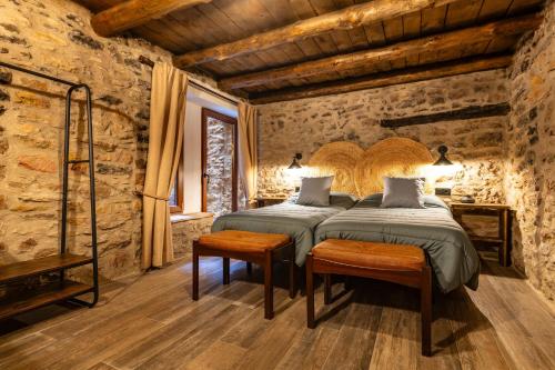 two beds in a room with stone walls and wooden floors at Masía La Parreta in Villafranca del Cid