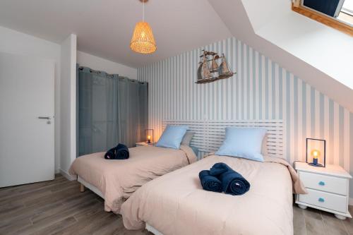 two beds in a bedroom with blue pillows on them at Ty Laouen Gite Quiberon in Quiberon