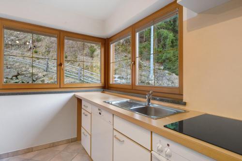 a kitchen with a sink and two windows at Sprenghof Ferienwohnung in Sarntal