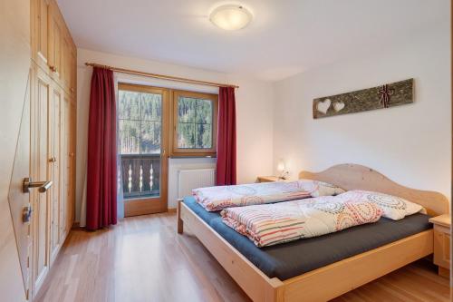a bedroom with a bed with red curtains and a window at Sprenghof Ferienwohnung in Sarntal