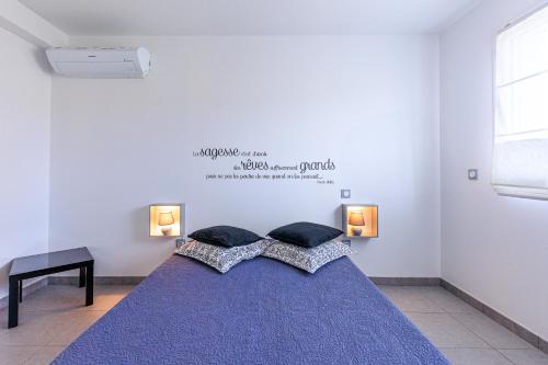 a bedroom with a blue bed with two pillows at Maison La Dune, Piscine et Jardin in Messanges