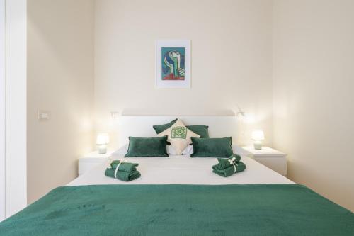 a large white bed with green sheets and pillows at Sa Mariposa in Cagliari