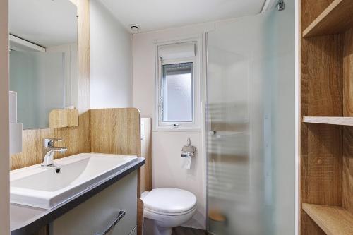 a bathroom with a white sink and a toilet at Mobile Home du Bois Dormant in Saint-Jean-de-Monts
