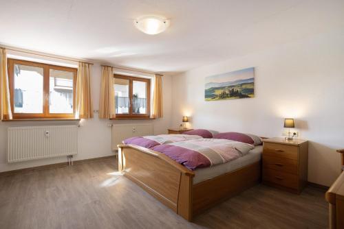 a bedroom with a large bed and two windows at Landhaus Moos in Argenbühl
