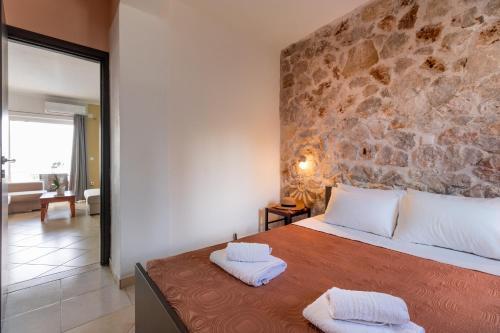 a bedroom with a stone wall and a bed with two towels at Apartment with Sea view B in Tsoukalades