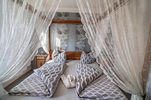 a bedroom with white curtains and a bed with pillows at Haus Ruther - Wohnung 1 in Bad Saulgau