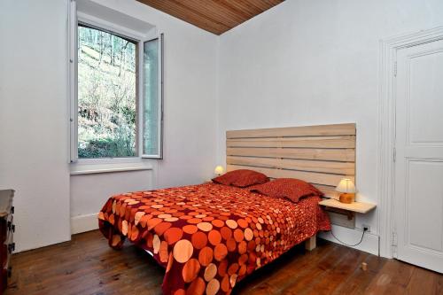 a bedroom with a bed with an orange comforter and a window at Gite Decauville in Uchentein