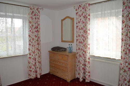 a room with two windows with curtains and a dresser at Landhotel Rangau Gasthof & Brennerei in Markt Erlbach