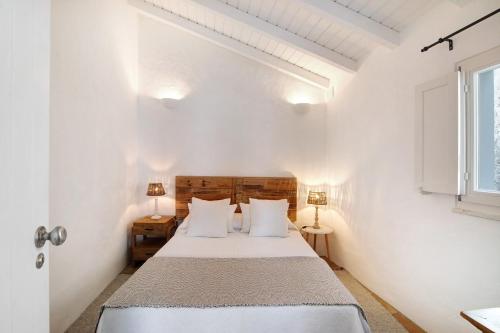 a white bedroom with a bed and two lamps at Casa de Benafim 1 in Benafim