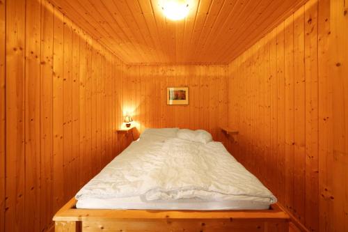 a bedroom with a bed in a wooden room at Bungalow 34 - Kimbucht in Reichendorf