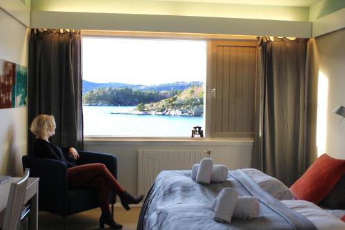 a woman sitting in a chair in a room with a window at Oscarsborg Castle Hotel & Resort in Drøbak