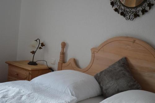a bedroom with a bed with a wooden headboard and a mirror at Landhotel Rangau Gasthof & Brennerei in Markt Erlbach