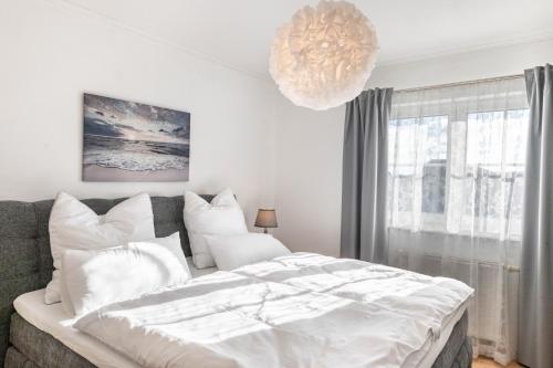 a white bedroom with a large bed and a chandelier at Casa Meeresbrise Marlow in Marlow