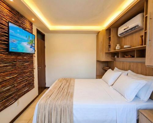 a bedroom with a bed and a tv on a wall at Hotel Natal Ponta Negra Sun in Natal