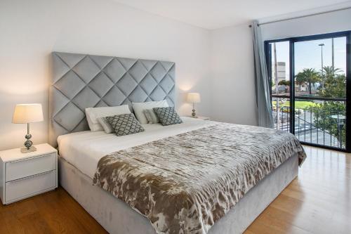 a bedroom with a large bed and a large window at Apartamento Forum View in Funchal