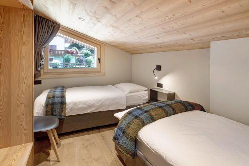 a small room with two beds and a window at Aria di Casa Piazzi in Valdisotto