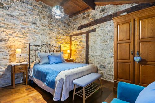 a bedroom with a bed and a stone wall at Teixo in Vega de Logares