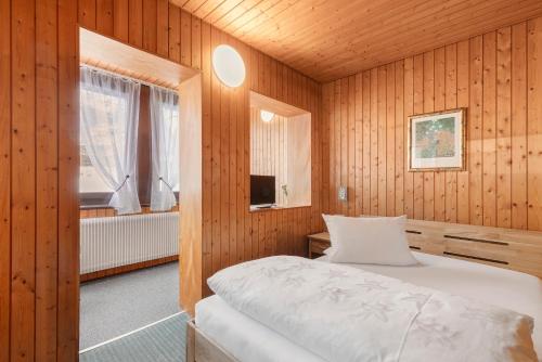 a bedroom with wooden walls and a bed with a window at Hotel Garni Siedlerstube in Nürtingen