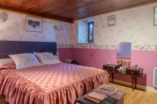 a bedroom with a large bed with pink walls at Logis des Tilleuls in Saint-Mathieu