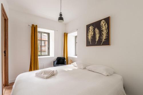 a bedroom with a white bed with a picture on the wall at L'écrin De La Sèvre in Cugand