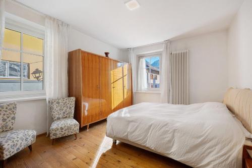 a bedroom with a bed and a cabinet and two chairs at Casa Mariotta in Castello di Fiemme