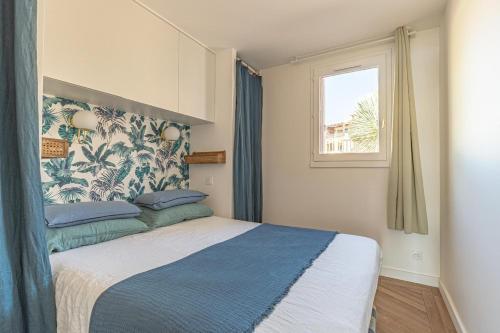 a bedroom with a bed with a blue and white blanket at Vue Mer Et Jardin in Théoule-sur-Mer