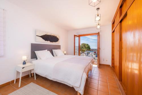 a bedroom with a white bed and a balcony at Es Port in Cala Ratjada