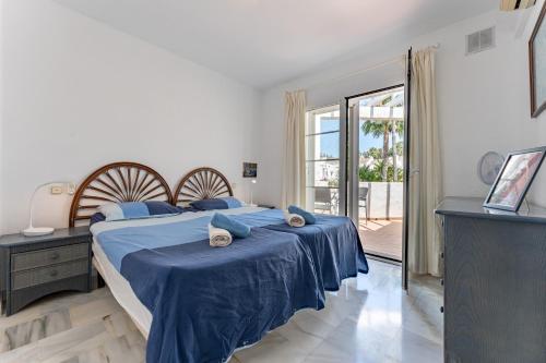 a bedroom with a bed with blue sheets and a window at Casa Karma in Mijas