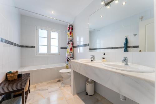 a bathroom with two sinks and a toilet and a mirror at Casa Karma in Mijas