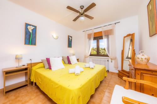 a bedroom with a yellow bed with a ceiling fan at Ses Serres in Santanyi