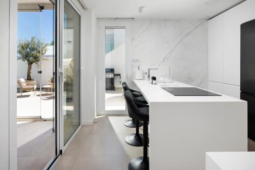 a kitchen with a white counter and black chairs at Casa Blanca in Torre del Mar