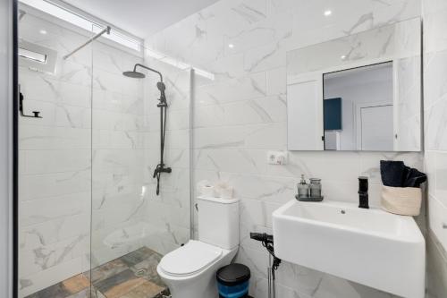 a white bathroom with a toilet and a sink at Casa sofia in Arrecife