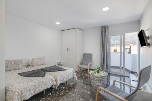 a bedroom with a bed and chairs and a balcony at Casa sofia in Arrecife