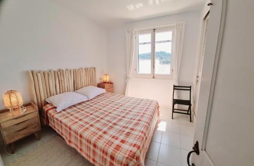 ein Schlafzimmer mit einem Bett, einer karierten Decke und einem Fenster in der Unterkunft El Ton Golf in Son Parc