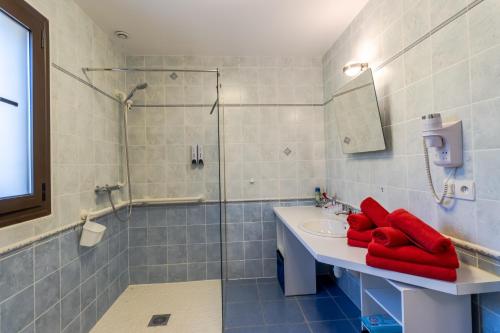a bathroom with a sink and a shower with red towels at Maison Liz in Castelnaud La Chapelle