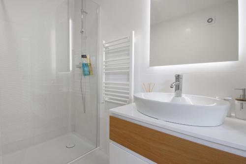 a white bathroom with a sink and a shower at Flor de Sá in Aveiro