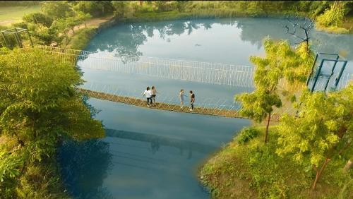 two people walking across a bridge over a pond at Tathastu Pench in Khawāsa