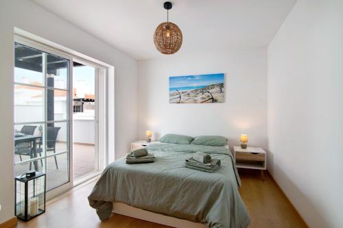 a white bedroom with a bed and a balcony at Vista Mar in Cabanas de Tavira