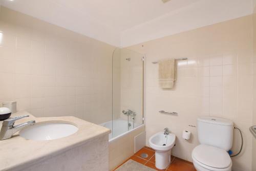 a white bathroom with a sink and a toilet at Casa do Ouriço - Cabanas Tavira in Tavira
