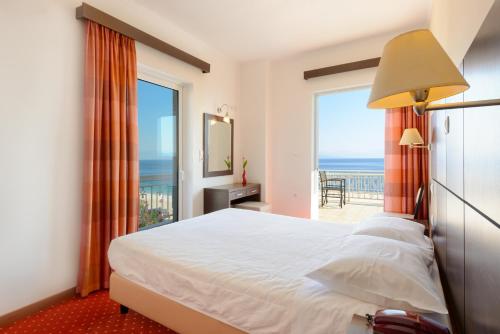 a bedroom with a bed and a view of the ocean at Akrata Beach Hotel in Akrata