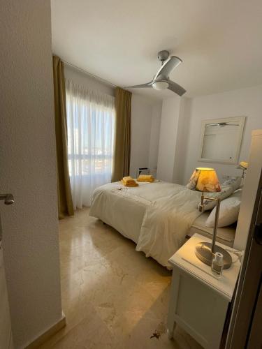 a bedroom with a bed and a table with a lamp at El Portil Pinares in El Portil