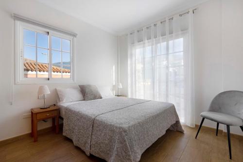 a bedroom with a bed and a chair and a window at Casa Luz in La Luz