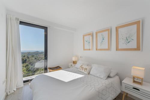 a white bedroom with a bed and a large window at Dúplex Bellas Vistas in Ojén