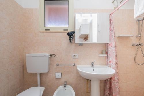 a bathroom with a sink and a toilet and a window at Villa Privata Spiaggia Del Sole in Porto Cesareo