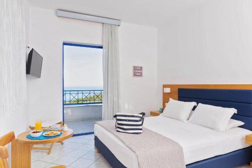 a bedroom with a bed and a view of the ocean at Karras Star Hotel in Evdilos