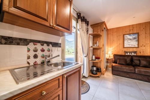a kitchen with a sink and a couch in a room at Au Rêve Savoyard 1 - 2 personnes in Morillon