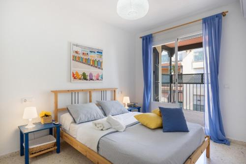 a bedroom with two beds with blue curtains and a window at Camaleón 7 in Chipiona